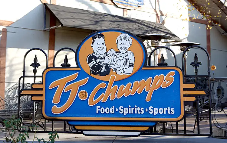 Blue and orange restaurant sign featuring a cartoon chef logo and the words Food • Spirits • Sports.
