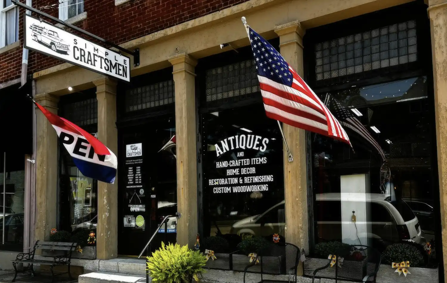 Brick storefront of an antiques shop with an American flag displayed outside.