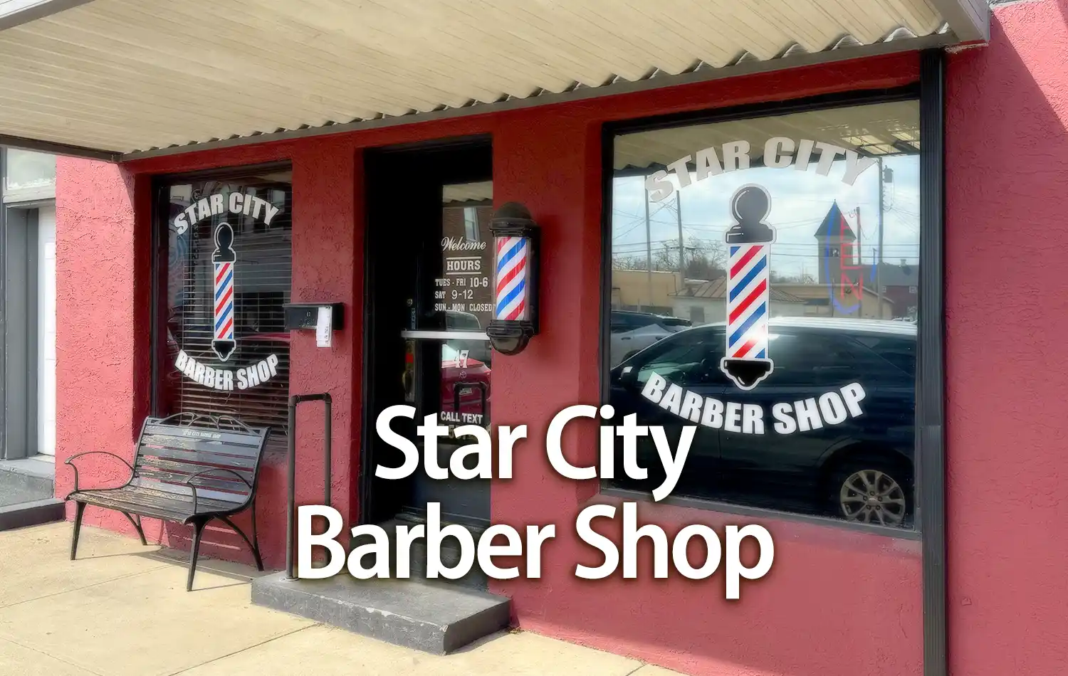 Red storefront for Star City Barber Shop with barber-pole graphics in the windows and a bench outside.